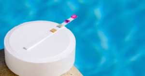 Testing swimming pool water using test strips to check chlorine and pH levels