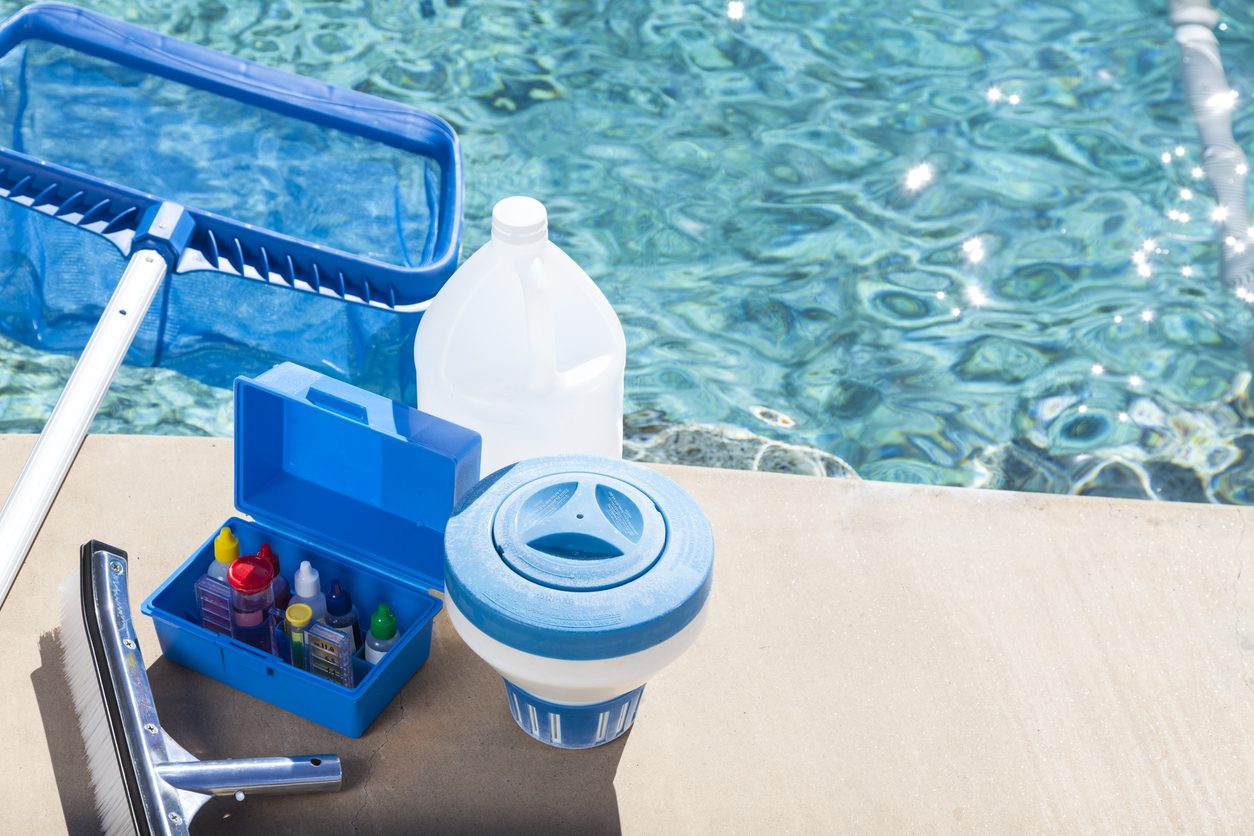 Testing swimming pool water using test strips to check chlorine and pH levels